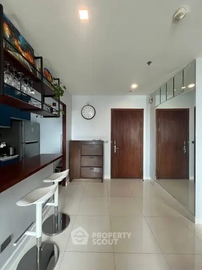 Modern kitchen with sleek bar stools and mirrored wall in a stylish apartment.