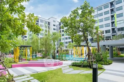 Modern residential building with lush garden and pool area, perfect for urban living.
