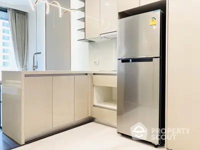 Sleek modern kitchen with high-end stainless steel refrigerator, ample cabinet space, and minimalist design in a luxurious apartment.