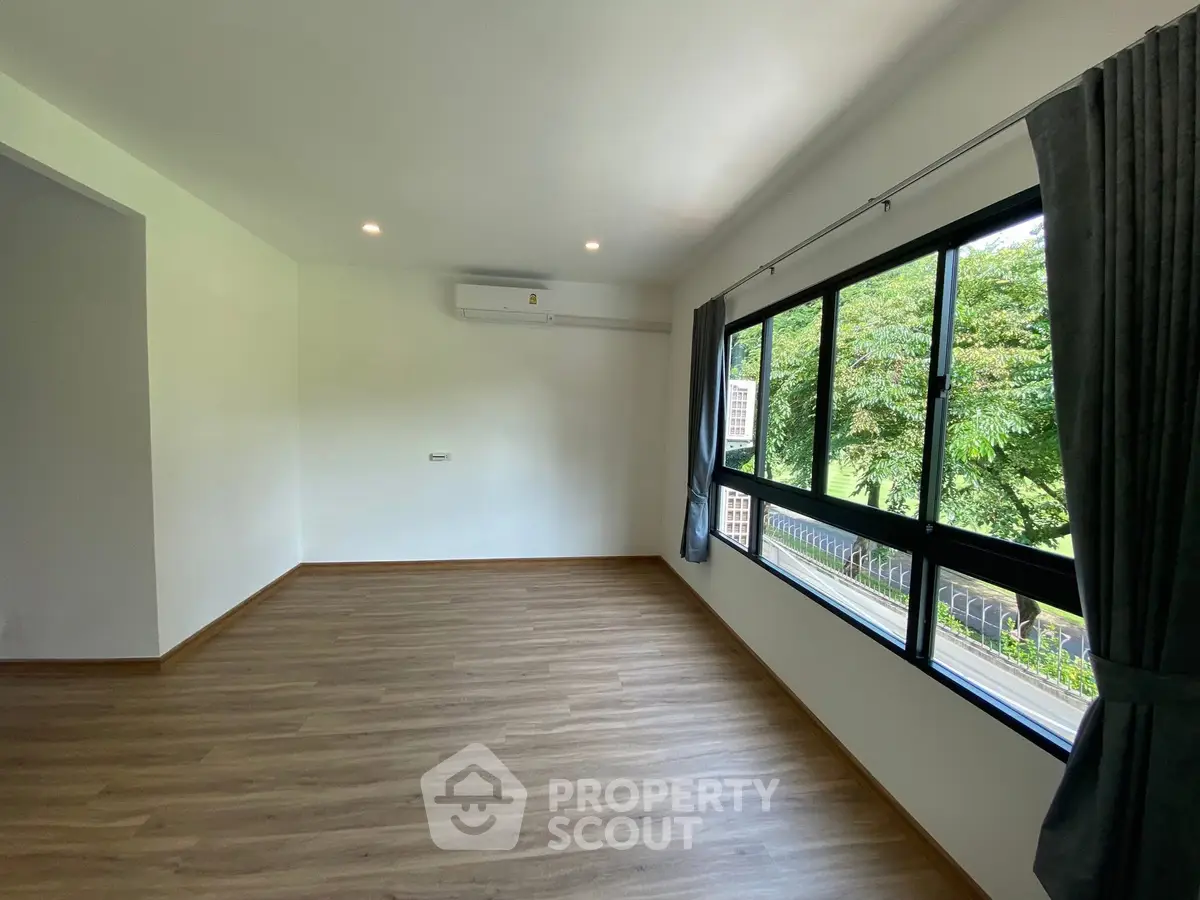 Spacious living room with large windows and serene garden view.