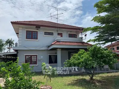 Charming two-story house with red-tiled roof and lush garden, perfect for family living.