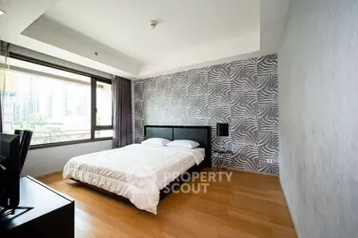 Modern bedroom with large window and stylish wallpaper, featuring wooden flooring and contemporary decor.