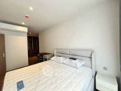 Spacious bedroom with modern furnishings and ample natural light, featuring a comfortable bed and built-in storage.