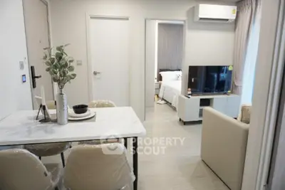 Modern apartment interior with open living room and dining area, featuring sleek furniture and neutral tones.