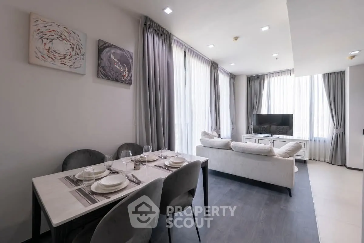 Modern open-plan living room with elegant dining area and large windows