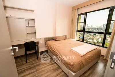 Modern bedroom with city view, featuring a cozy bed and study desk, perfect for urban living.