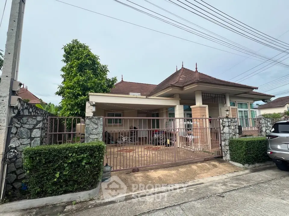 Charming single-story house with gated driveway and lush greenery in a serene neighborhood.