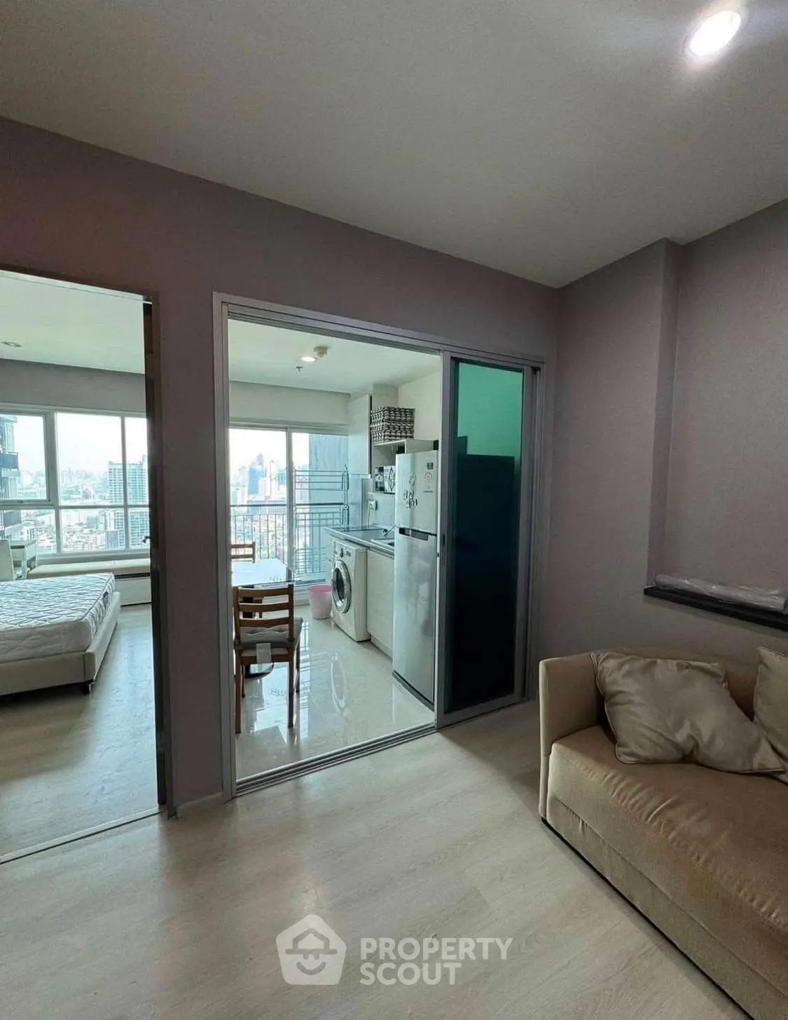 Modern apartment with open kitchen, living room, and bedroom, featuring city views and natural light.