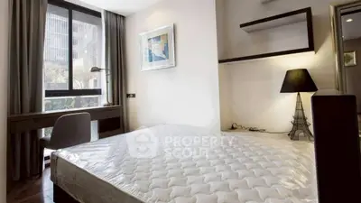 Modern bedroom with large window and stylish decor in urban apartment.