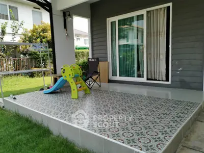 Charming patio with playful slide and lush garden view, perfect for family relaxation.