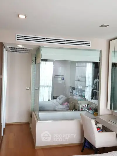 Modern bedroom with glass-enclosed bathroom and sleek wooden flooring