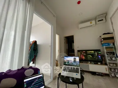 Cozy living room with modern decor and air conditioning, featuring a laptop setup and entertainment area.