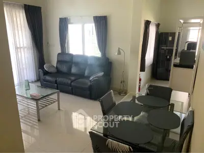 Modern living room with sleek furniture and dining area, featuring large windows and natural light.