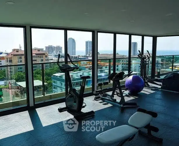 Spacious gym with panoramic city views and modern fitness equipment.