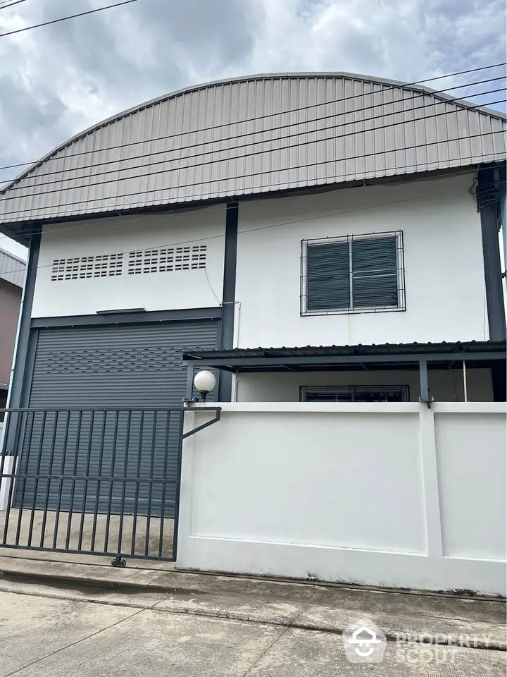 Modern industrial-style building with secure gated entrance and large roller door.