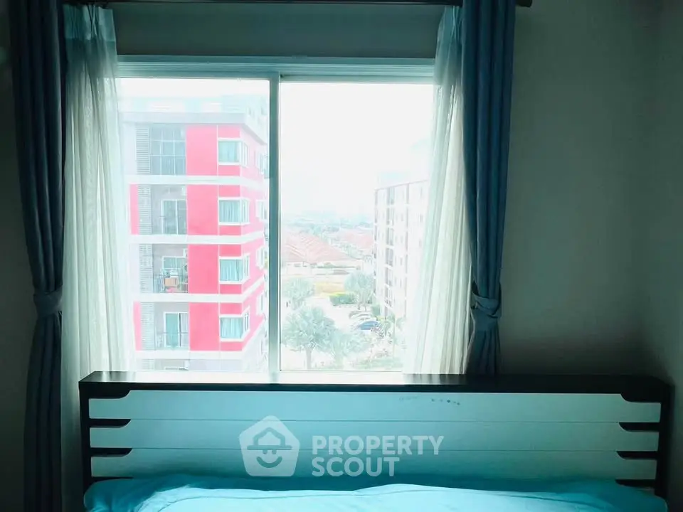 Bright bedroom with large window offering city view in modern apartment