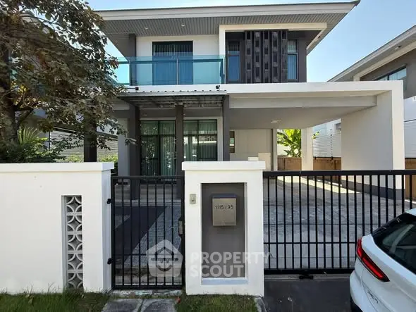 Modern two-story house with gated entrance and driveway in a serene neighborhood.