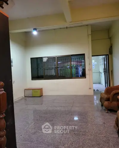 Spacious living room with tiled flooring and large window, ideal for cozy gatherings.