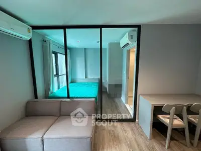 Modern studio apartment with glass partition, cozy living area, and sleek furnishings.