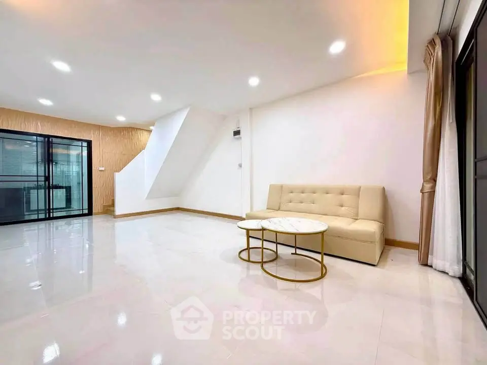 Spacious modern living room with elegant sofa and stylish coffee table, featuring bright lighting and sleek flooring.