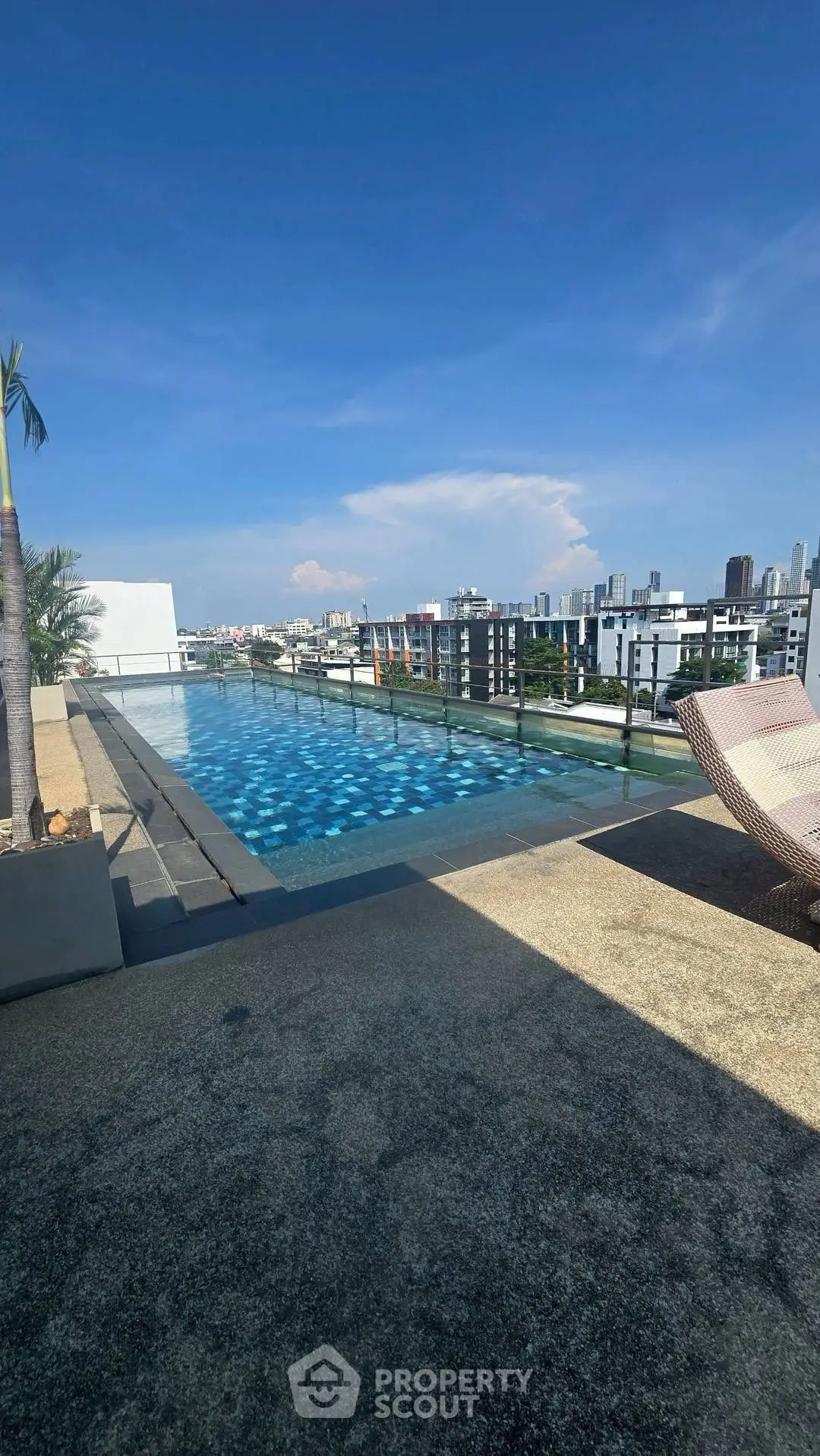 Stunning rooftop pool with panoramic city views and clear blue skies.
