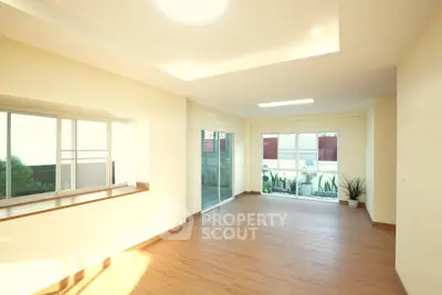 Spacious sunlit living room with large windows and wooden flooring