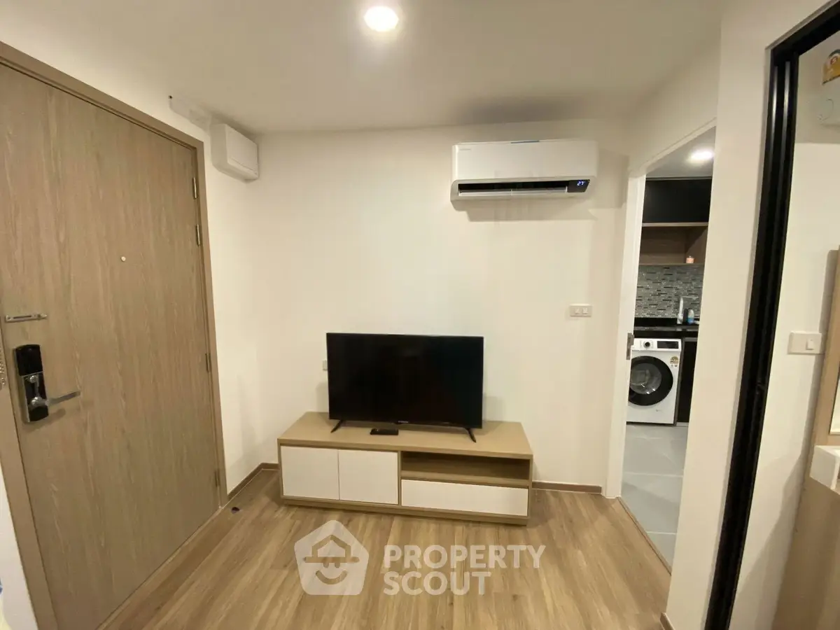 Modern living room with TV, air conditioning, and wooden flooring in a stylish apartment.