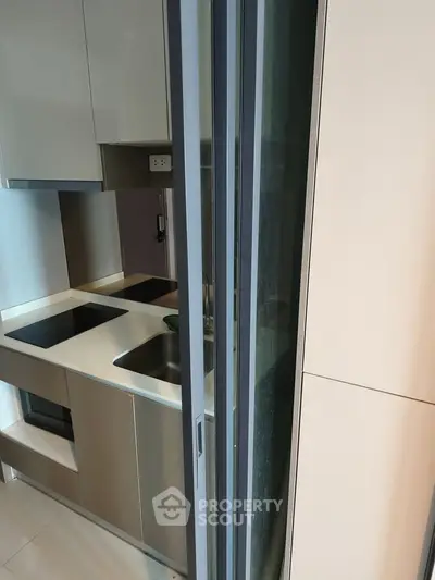 Modern compact kitchen with sleek cabinetry and built-in appliances in a stylish apartment.