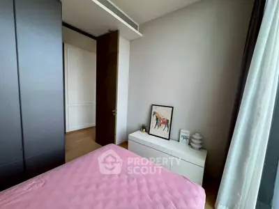 Cozy bedroom with modern decor and ample natural light, featuring a stylish wardrobe and elegant artwork.