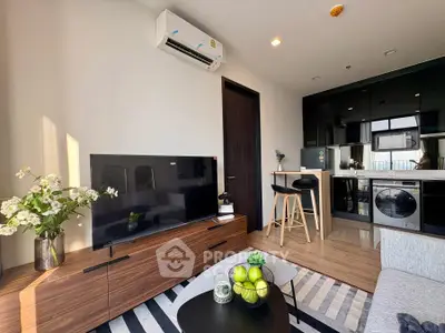 Modern living room with sleek furniture and open kitchen layout, featuring a stylish TV setup and air conditioning.