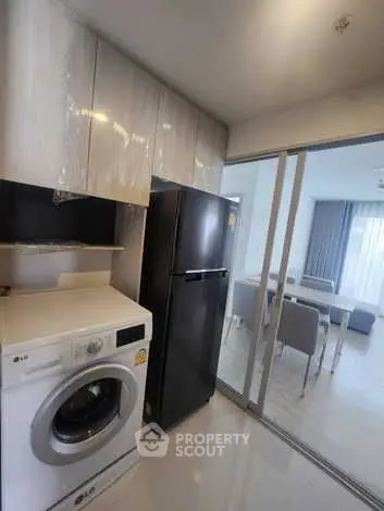 Modern kitchen with washing machine and fridge in sleek apartment
