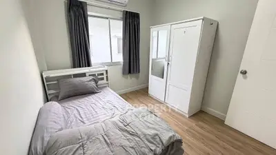 Cozy bedroom with wooden flooring, single bed, and wardrobe in a bright apartment.