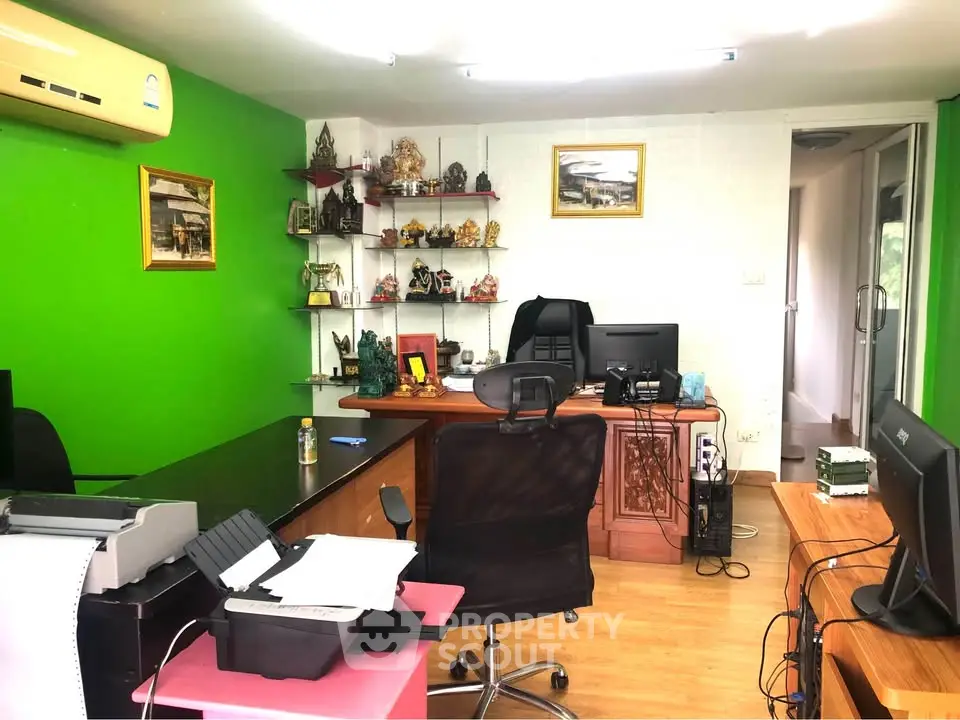 Modern home office with vibrant green accent wall, ergonomic chair, and organized desk setup.