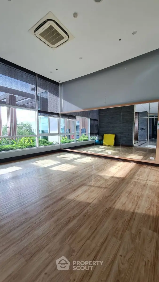 Spacious fitness studio with mirrored wall and wooden flooring in modern building.