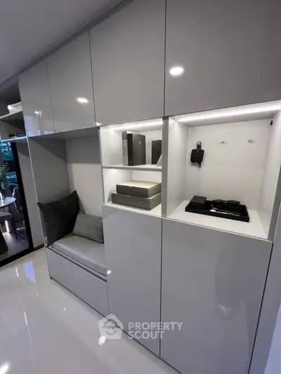 Sleek modern living room with built-in glossy white cabinets and cozy seating nook, perfect for urban living.