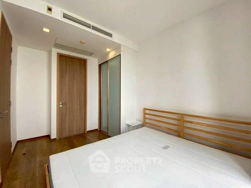 Spacious minimalist bedroom with wooden flooring and modern design.