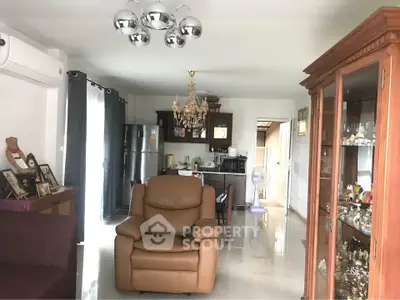 Spacious living room with elegant chandelier and modern kitchen appliances