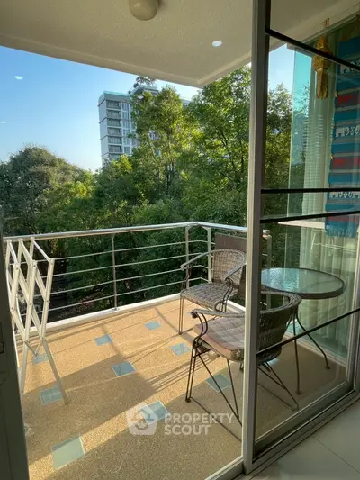 Charming balcony with outdoor seating and lush green view, perfect for relaxation.