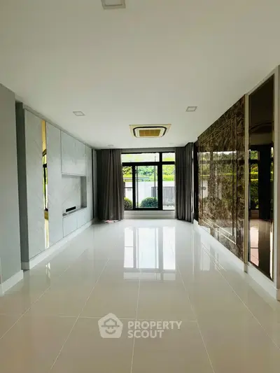 Spacious modern living room with large windows and elegant marble accents.