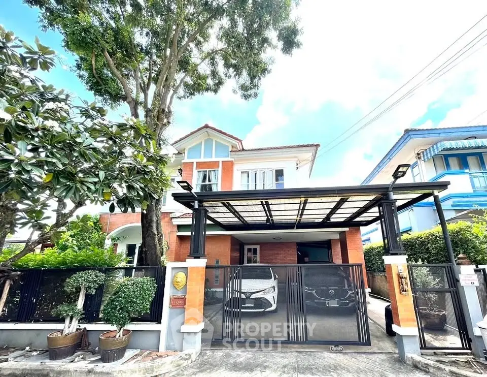 Charming two-story house with gated driveway and lush greenery
