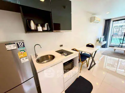 Modern compact kitchen with sleek appliances and cozy dining area in bright apartment.