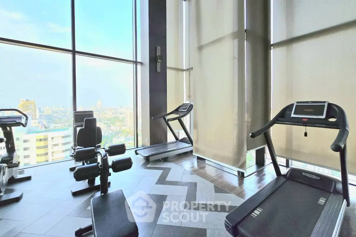 Modern gym with city view and state-of-the-art equipment in luxury high-rise building.