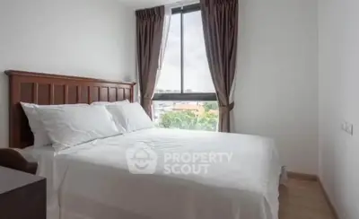 Cozy bedroom with large window and elegant curtains, offering a serene view and inviting natural light.