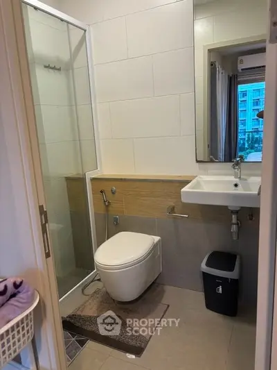 Modern bathroom with sleek fixtures and a large mirror, featuring a compact design and neutral tones.