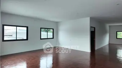 Spacious empty room with polished wooden floors and large windows