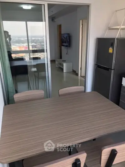 Modern dining area with sleek table and chairs, adjacent to a bright living room with a view.