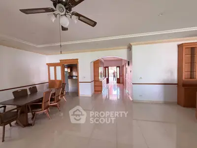 Spacious open-plan living and dining area with elegant wooden furniture and ceiling fan.