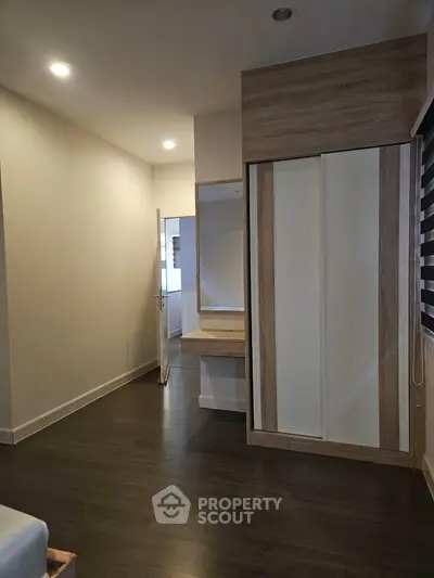 Modern bedroom with wooden flooring and built-in wardrobe, featuring a minimalist design.