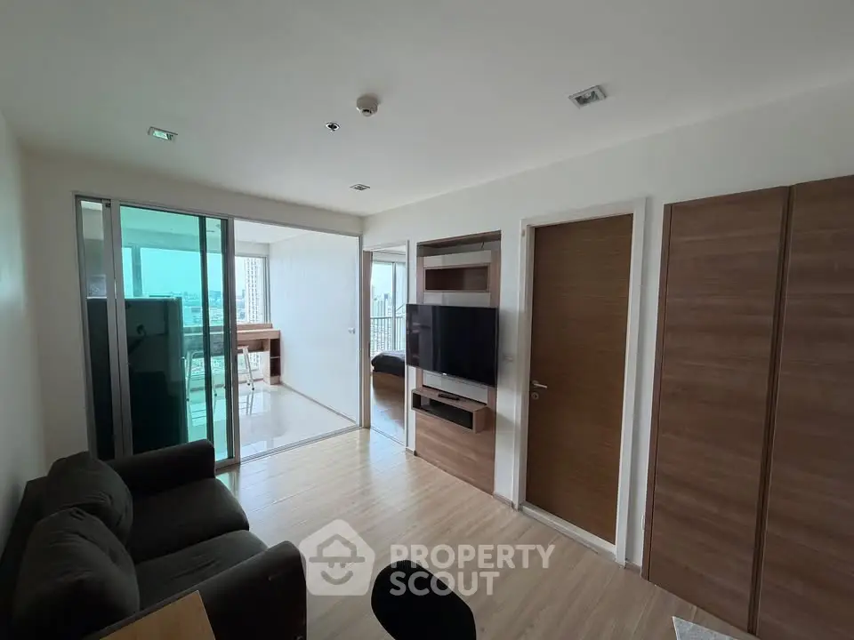 Modern living room with sliding glass doors leading to a bright balcony, featuring sleek wooden accents and a cozy sofa.