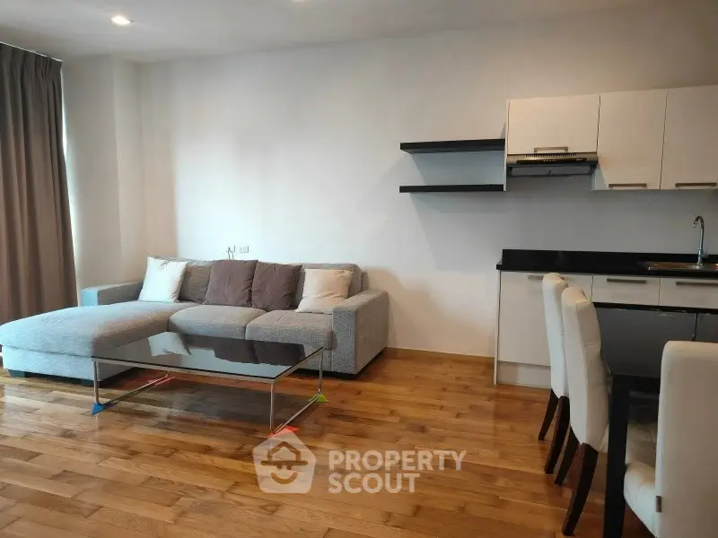 Modern living room with sleek kitchen and cozy sofa in open layout apartment.